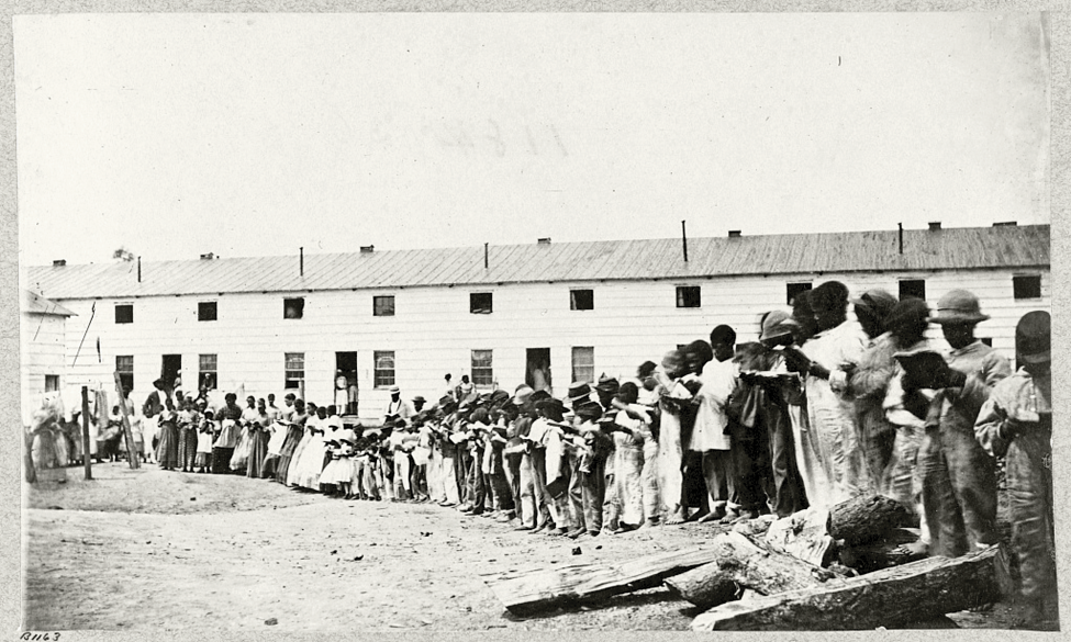 Black adults and children read books in front of a barracks building at Freedman’s Village. As many as 900 students were educated at the Village school. Photographed between 1862 and 1865. Source: Library of Congress.